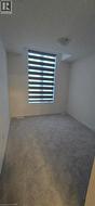 Empty room with a textured ceiling and dark carpet - 