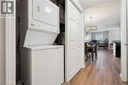 Laundry room featuring stacked washing machine and dryer, light wood-style flooring, and a chandelier - 