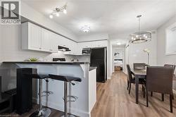 Kitchen with dark countertops, white cabinets, freestanding refrigerator, a kitchen breakfast bar, and pendant lighting - 