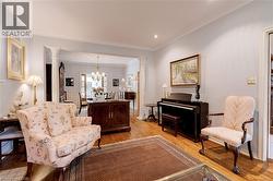 Living area with decorative columns, crown molding, light wood-style floors, a chandelier, and recessed lighting - 