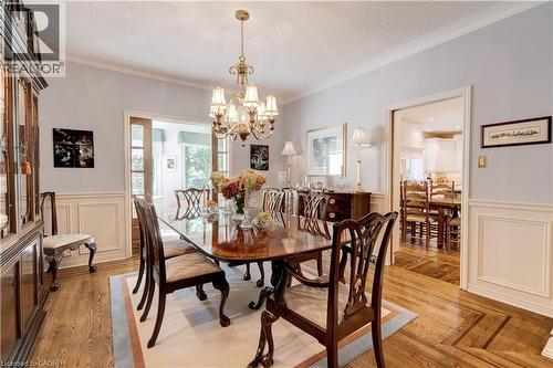 Dining area featuring a decorative wall, a wainscoted wall, ornamental molding, a chandelier, and light wood-style floors - 166 Maple Grove Drive, Oakville, ON - Indoor Photo Showing Dining Room