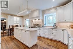 Kitchen with white cabinetry, an island with sink, backsplash, and recessed lighting - 