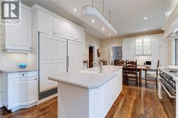 Kitchen with white cabinets, high end appliances, recessed lighting, dark wood finished floors, and tasteful backsplash - 