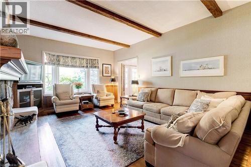 Living room featuring wood finished floors, beam ceiling, and a stone fireplace - 166 Maple Grove Drive, Oakville, ON - Indoor Photo Showing Living Room