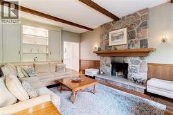 Living area featuring a wainscoted wall, a stone fireplace, wood finished floors, and beam ceiling - 