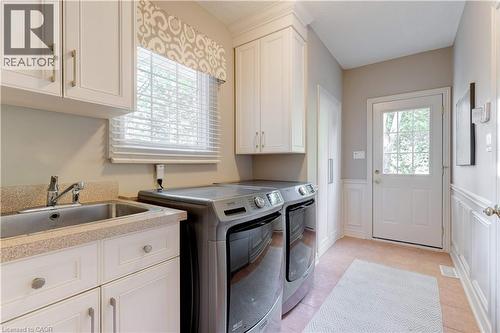 Laundry room featuring light tile patterned floors, a wainscoted wall, cabinet space, washer and dryer, and a decorative wall - 166 Maple Grove Drive, Oakville, ON - Indoor Photo Showing Laundry Room