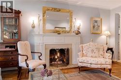 Living area with wood finished floors, ornamental molding, and a fireplace with flush hearth - 