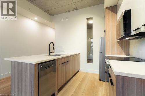 Kitchen with modern cabinets, stainless steel appliances, a peninsula, light stone counters, and light wood-style floors - 24 Augusta Street Unit# 305, Hamilton, ON - Indoor Photo Showing Kitchen