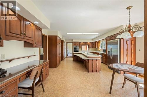 Kitchen with a breakfast bar, brown cabinetry, light floors, hanging light fixtures, and recessed lighting - 6828 Third Line, Chatham, ON 