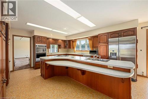 Kitchen featuring a breakfast bar, a kitchen island with sink, appliances with stainless steel finishes, light countertops, and light floors - 6828 Third Line, Chatham, ON - Indoor Photo Showing Kitchen With Double Sink