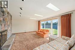 Carpeted living room featuring a stone fireplace and a textured ceiling - 