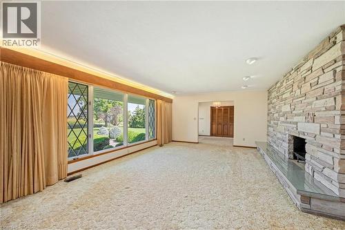 Unfurnished living room featuring a stone fireplace and light carpet - 6828 Third Line, Chatham, ON - Indoor With Fireplace