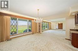 Unfurnished dining area with a chandelier, light carpet, and a baseboard radiator - 