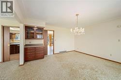 Spare room with light colored carpet and a chandelier - 