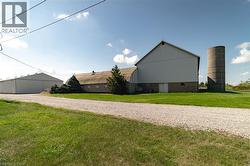 View of property exterior featuring a yard, an outdoor structure, a pole building, and gravel driveway - 