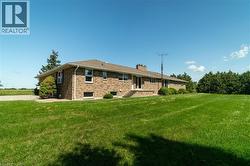 Back of house with a yard, brick siding, and a chimney - 