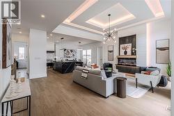 Great Room featuring Engineered Hardwood floors, a Coffered ceiling, Electric fireplace, and recessed LED  lighting - 