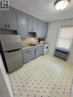 Kitchen with fridge, light floors, range, and radiator - 