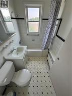 Full bath featuring tile walls, shower / bath combo with shower curtain, healthy amount of natural light, tile patterned floors, and radiator - 