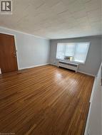 Spare room featuring wood finished floors, radiator, and crown molding - 