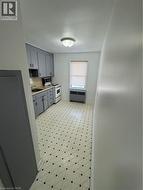 Kitchen featuring gray cabinets, range, radiator heating unit, light floors, and light countertops - 