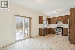 Kitchen with appliances with stainless steel finishes, light countertops, under cabinet range hood, and light tile patterned floors - 
