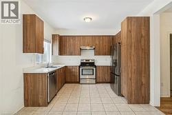 Kitchen featuring stainless steel appliances, light countertops, brown cabinets, and under cabinet range hood - 
