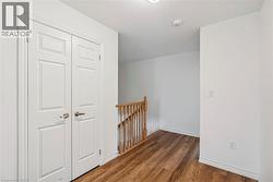 Hallway with an upstairs landing and dark wood-style floors - 
