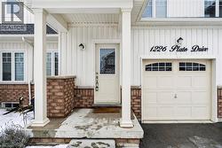 Entrance to property featuring covered porch, board and batten siding, a garage, and a shingled roof - 