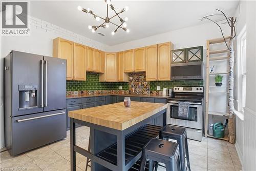 Kitchen featuring appliances with stainless steel finishes, light brown cabinetry, a chandelier, and light tile patterned floors - 313 Mary Street, Hamilton, ON - Indoor Photo Showing Kitchen