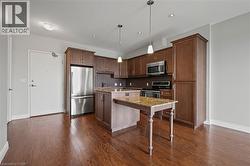 Kitchen featuring stainless steel appliances, a kitchen island, dark wood-style flooring, tasteful backsplash, and recessed lighting - 
