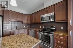 Kitchen with stainless steel appliances, backsplash, and light stone counters - 