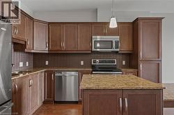 Kitchen featuring appliances with stainless steel finishes, dark wood-style floors, decorative backsplash, and decorative light fixtures - 