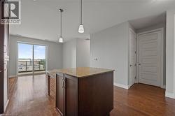 Kitchen with dark wood-style floors, pendant lighting, light stone countertops, and a kitchen island - 