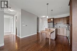 Kitchen featuring freestanding refrigerator, a kitchen island, tasteful backsplash, dark wood finished floors, and light stone countertops - 