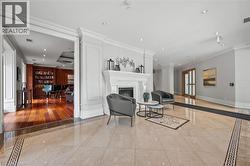 Living area with inlaid floor details, recessed lighting, ornamental molding, a glass covered fireplace, and decorative columns - 