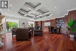 Living room featuring wood finished floors, beamed ceiling, crown molding, coffered ceiling, and a chandelier - 
