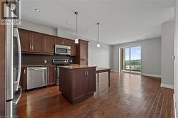 Kitchen featuring appliances with stainless steel finishes, a center island, dark wood-style floors, backsplash, and light stone countertops - 