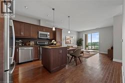 Kitchen featuring stainless steel appliances, a kitchen island, tasteful backsplash, dark wood-style floors, and light stone countertops - 