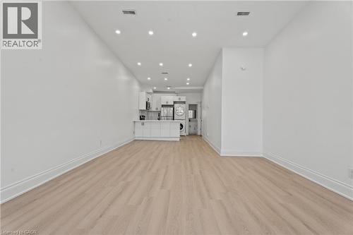 Unfurnished living room with light wood-style floors, recessed lighting, and stacked washing machine and dryer - 93 John Street S, Hamilton, ON 