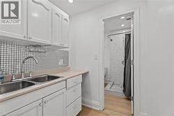 Kitchen featuring white cabinetry, light countertops, light wood-type flooring, backsplash, and recessed lighting - 