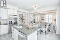 Kitchen featuring white cabinets, a sink, a kitchen island with sink, stainless steel appliances, and open floor plan - 