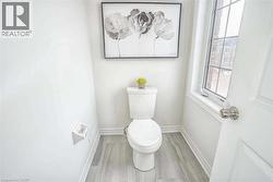 Bathroom featuring baseboards, toilet, and wood finished floors - 