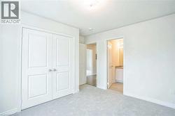 Unfurnished bedroom featuring a closet, light carpet, baseboards, connected bathroom, and a textured ceiling - 