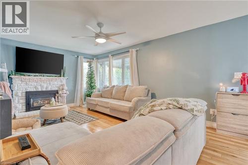 Living room with ceiling fan, a fireplace, and light wood-type flooring - 99 East 36Th Street, Hamilton, ON - Indoor Photo Showing Living Room With Fireplace