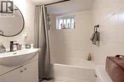Bathroom with vanity, tile walls, shower / bath combo with shower curtain, and backsplash - 