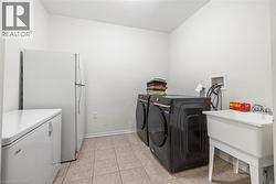 Laundry area featuring washing machine and dryer and light tile patterned flooring - 
