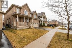 View of front facade featuring covered porch, brick siding, driveway, a front lawn, and a residential view - 