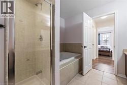 Ensuite bathroom featuring a stall shower, a bath, vanity, and light tile patterned flooring - 