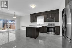Kitchen with appliances with stainless steel finishes, light countertops, plenty of natural light, and dark brown cabinetry - 